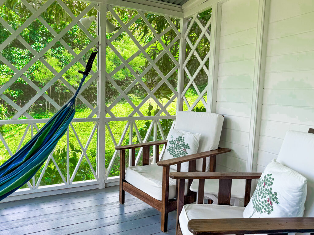 Covered private balcony of a Balcony Room with table, chairs and hammock