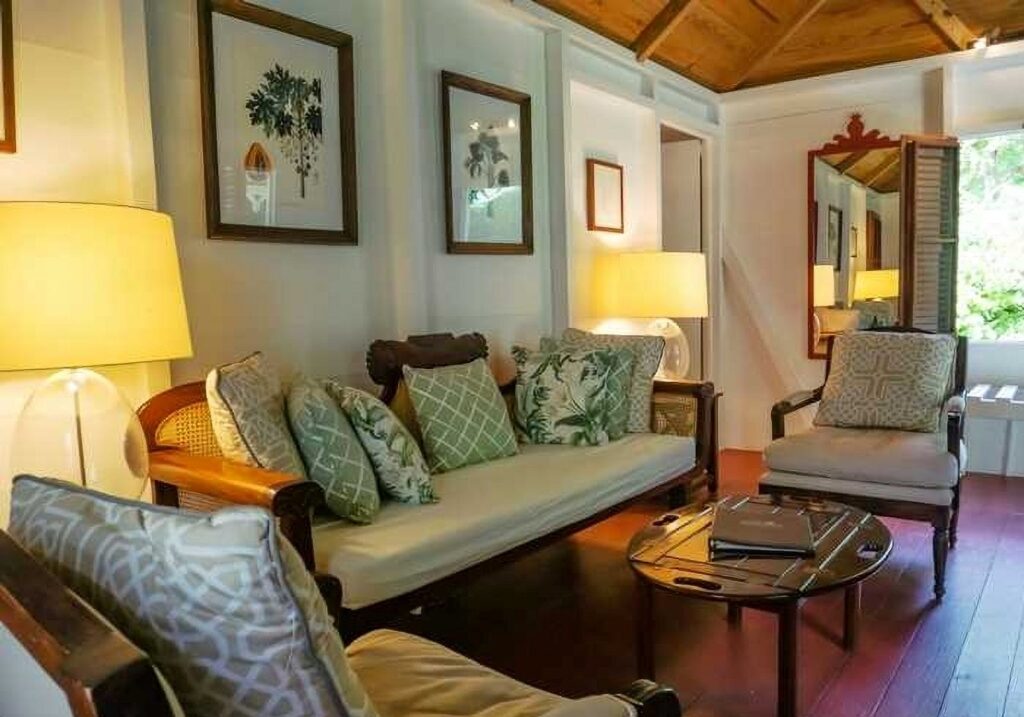 Sitting room of a three-person gingerbread cottage, with cane sofa and timber ceiling