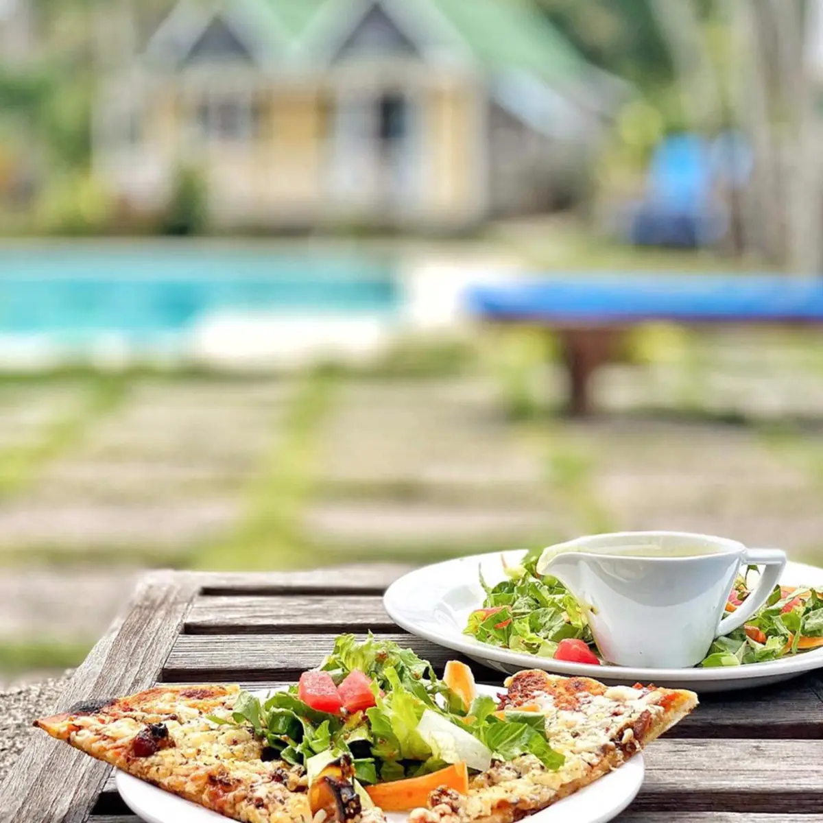 A wood-fired pizza and a fresh salad on a table at Hermitage Nevis