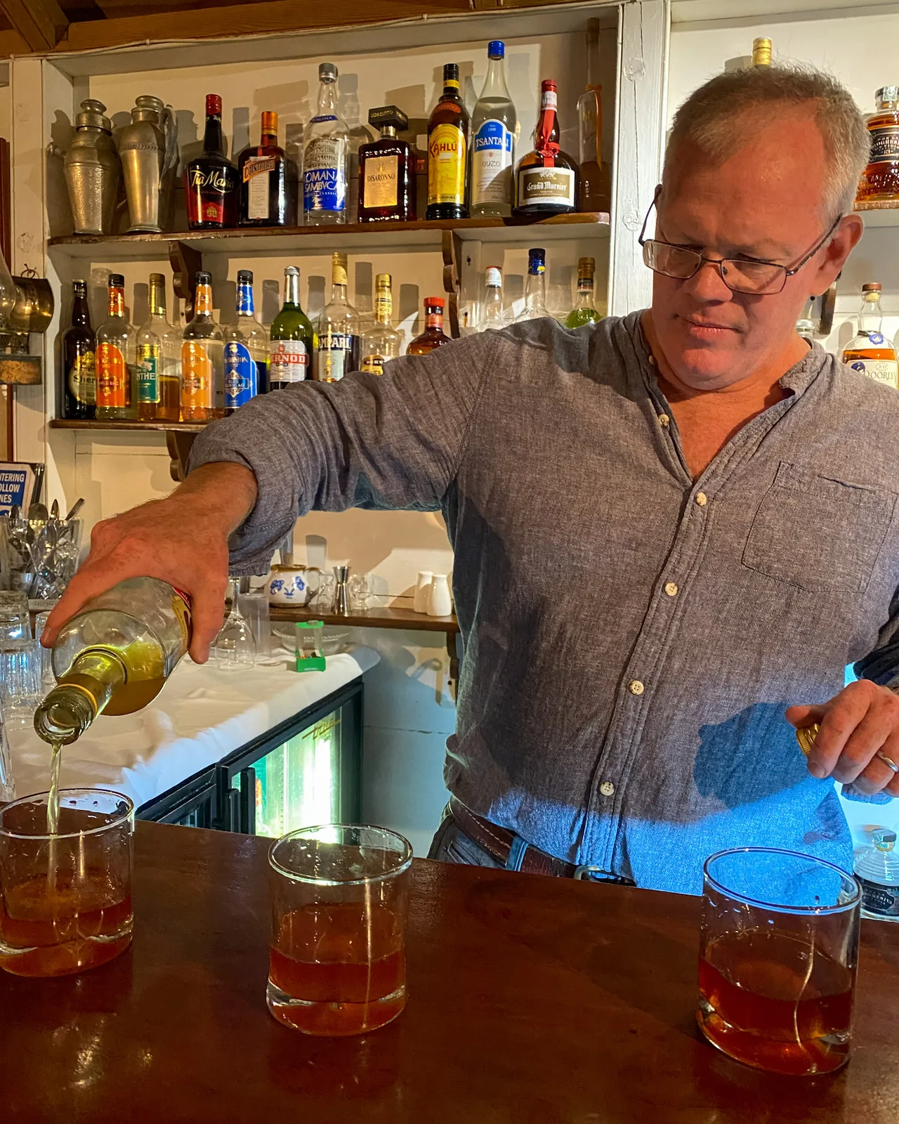 Richie Lupinacci pouring a drink at the honesty bar in the Great House at Hermitage Nevis