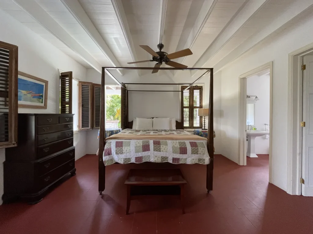 Bedroom at Rose Villa with a four-poster bed, a chest of drawers and a door through to its bathroom.
