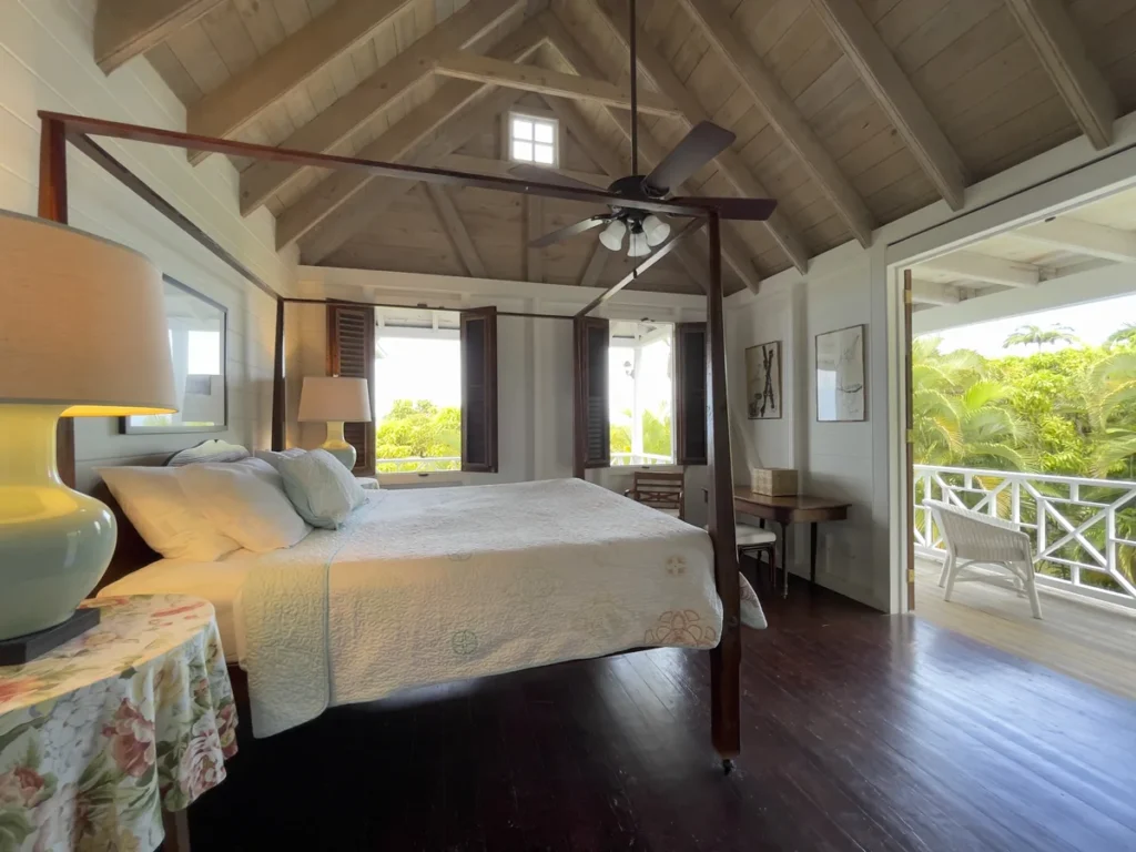 Bedroom at Rose Villa with a four-poster bed, a writing desk and doors opening onto the verandah.