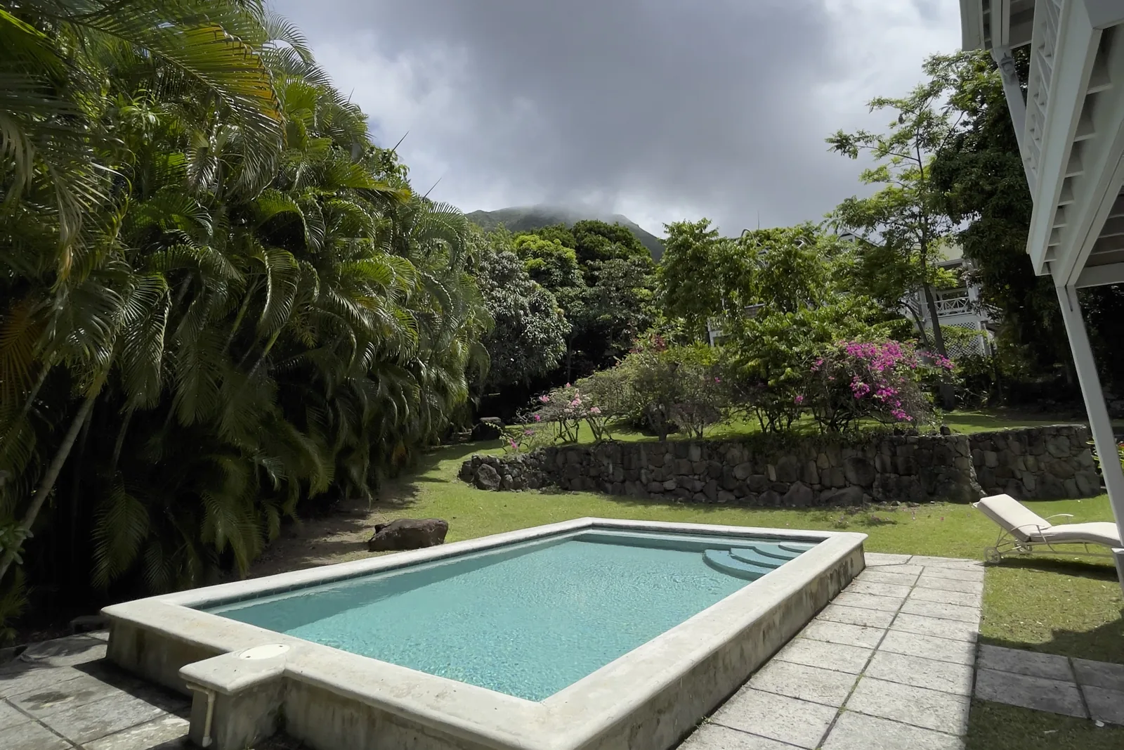 The private pool at Rose Villa in its garden, with the paved terrace and a sun lounger