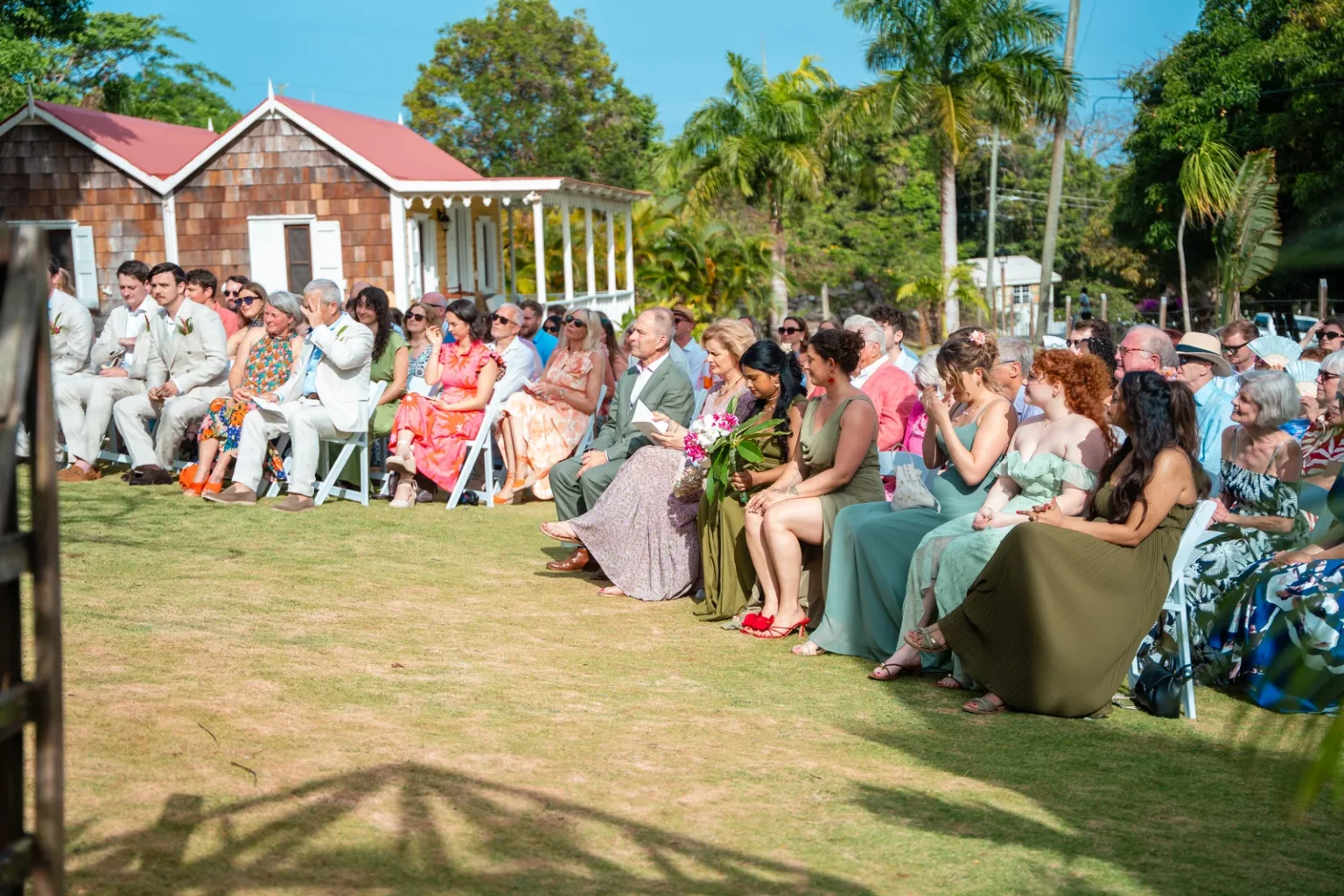 Wedding guests seated for an outdoor ceremony beside the buildings of Hermitage Nevis