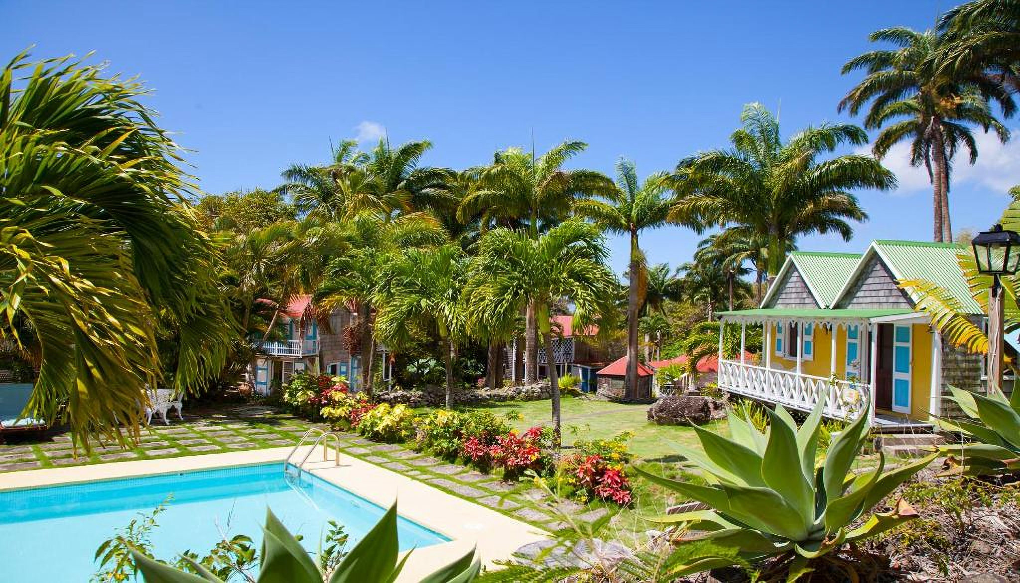 The pool, gardens and gingerbread cottages at Hermitage Nevis, framed by palms
