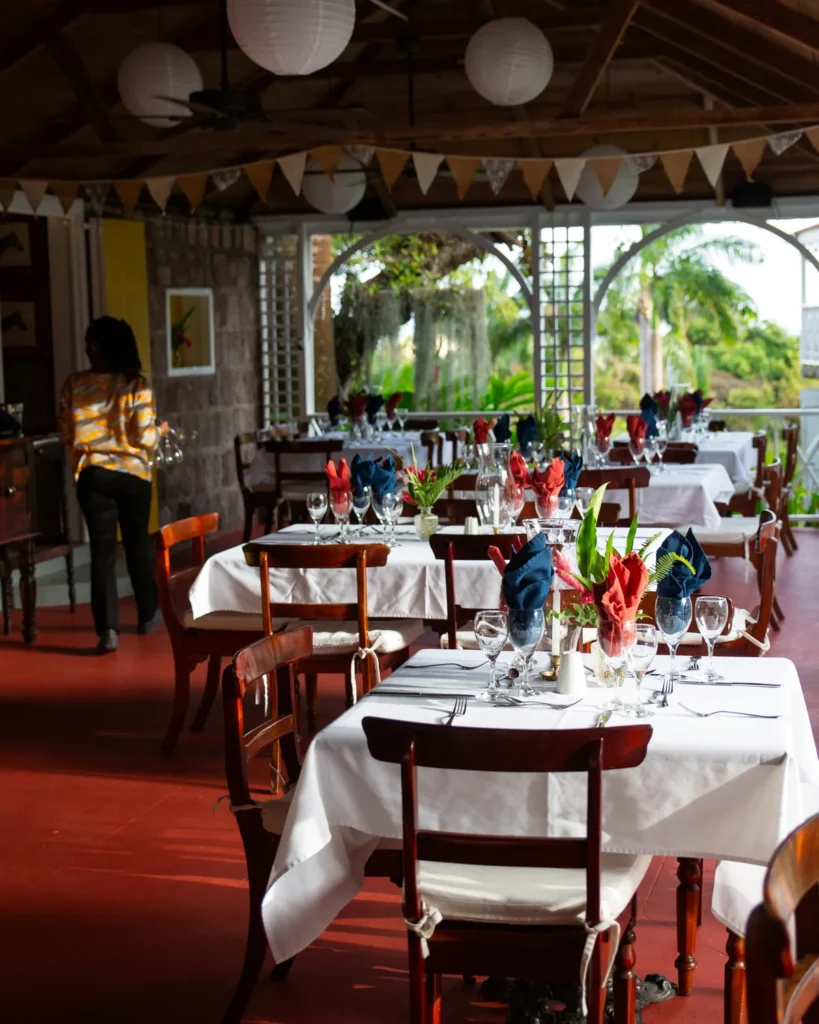 Tables laid for dinner on the open dining verandah at Hermitage Nevis