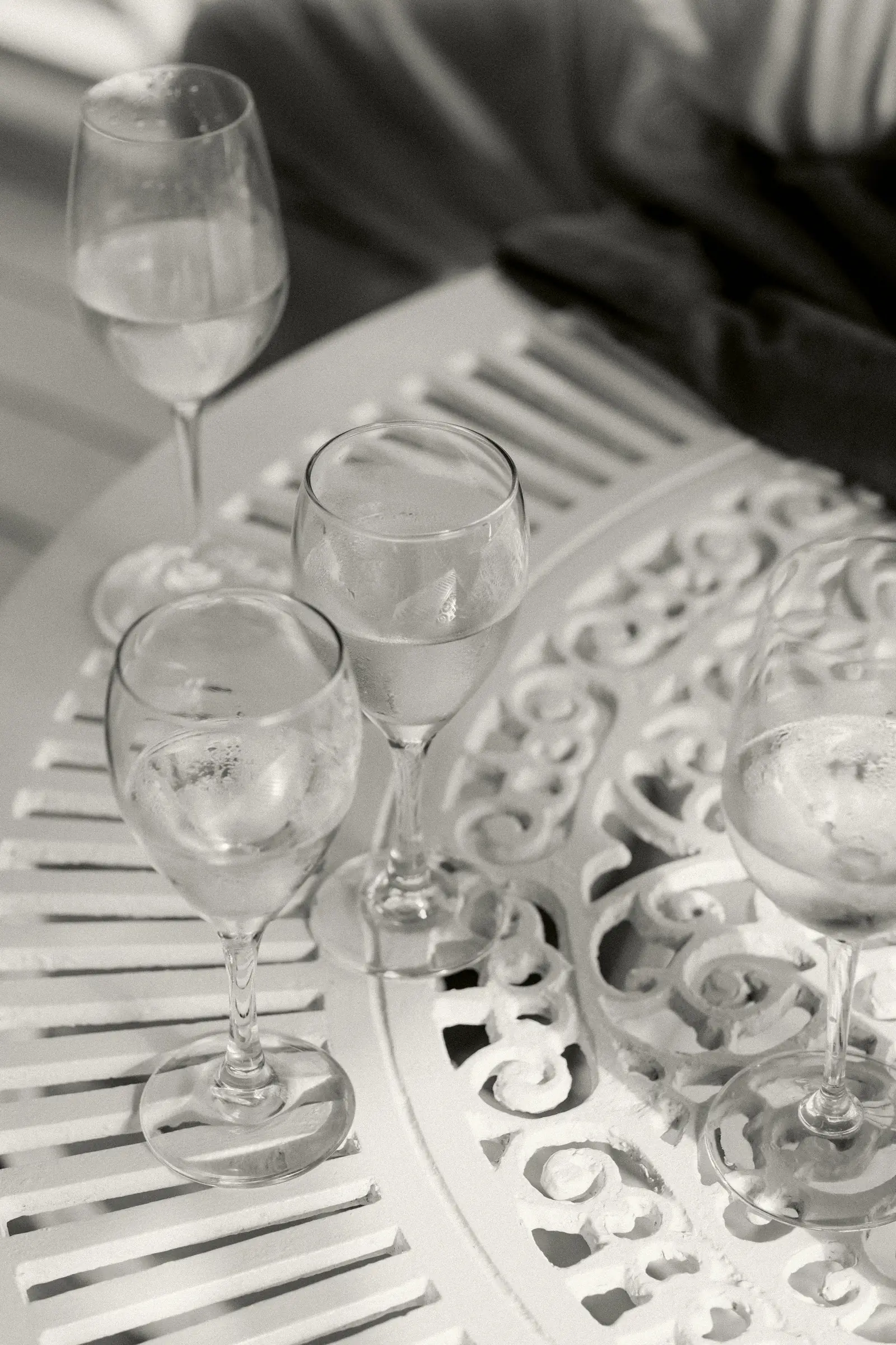 Four glasses of water standing on an ornate white cast iron garden table